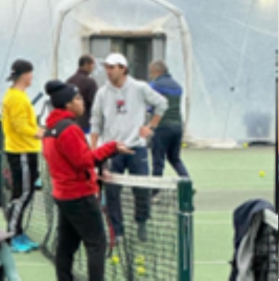 Photo of Javier Martinez stood at the net in a tennis bubble with a player