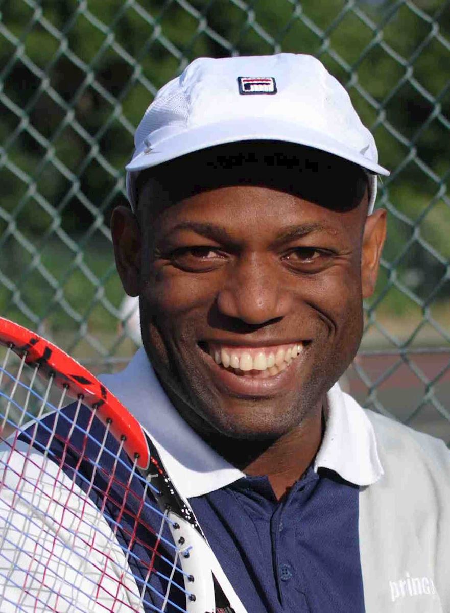 Photo of Rolando with a white baseball cap and tennis racket